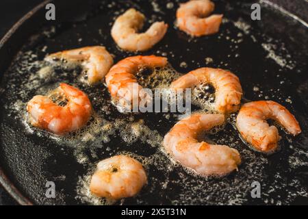 Nahaufnahme großer Garnelen, die in kochendem Öl in einer gusseisernen Pfanne gebraten wurden. Köstliches mediterranes Essen. Ausgewählter Fokus. Hochwertige Fotos Stockfoto