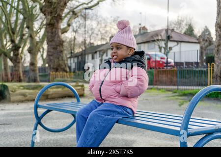 Mädchen (2-3) sitzt auf der Bank auf dem Spielplatz Stockfoto