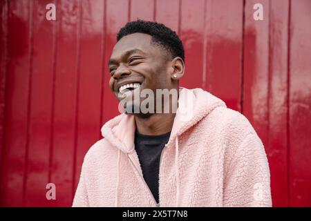 Lächelnder junger Mann mit rosa Hoodie Stockfoto