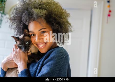 Porträt einer lächelnden Frau, die Katze zu Hause hält Stockfoto