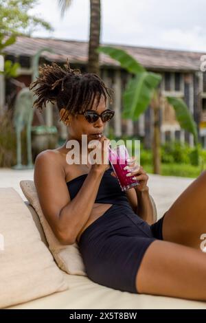 Frau im Badeanzug trinkt Smoothie auf der Terrasse Stockfoto