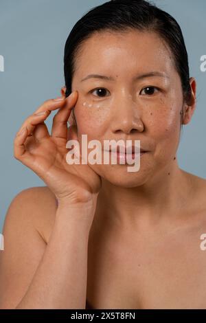 Porträt einer mittelerwachsenen Frau, die Creme unter die Augen aufträgt Stockfoto