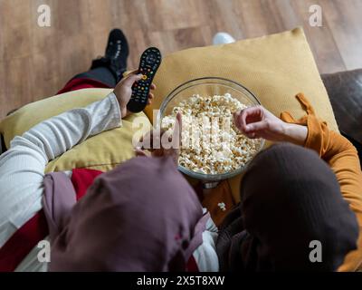 Blick auf Freunde, die auf dem Sofa sitzen und Popcorn essen Stockfoto