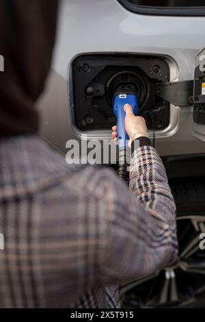 Frau, die Elektroauto auflädt, über die Schulter Stockfoto