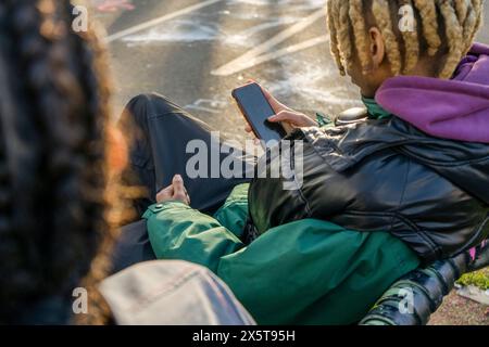 Junger Mann, der draußen sitzt und telefoniert Stockfoto