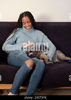 Frau streichelt zu Hause auf dem Sofa Französisch Bulldogge Stockfoto