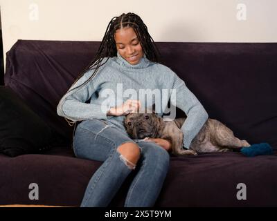 Frau streichelt zu Hause auf dem Sofa Französisch Bulldogge Stockfoto