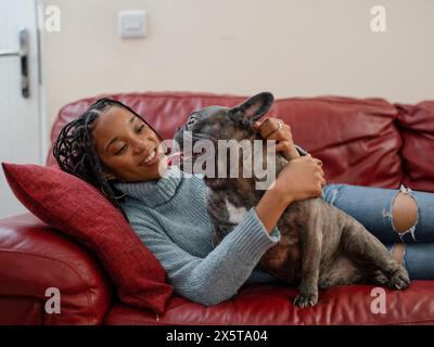 Frau und Hund ruhen auf Sofa im Wohnzimmer aus Stockfoto