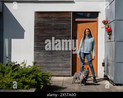 Lächelnde Frau posiert mit Hund vor dem Haus an sonnigen Tagen Stockfoto