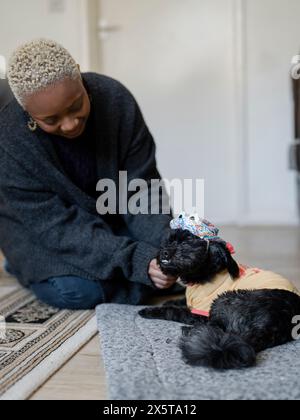 Frau, die Shih Tzu Poodle zuhause verkleidet Stockfoto