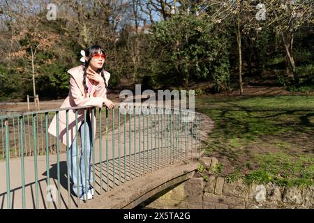 Junge Frau, die auf der Brücke im Park steht Stockfoto