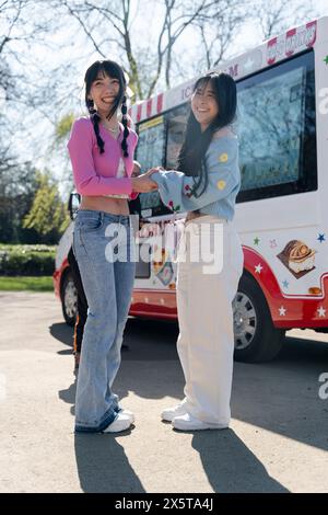 Junge Frauen stehen neben einem Eiswagen im Park Stockfoto