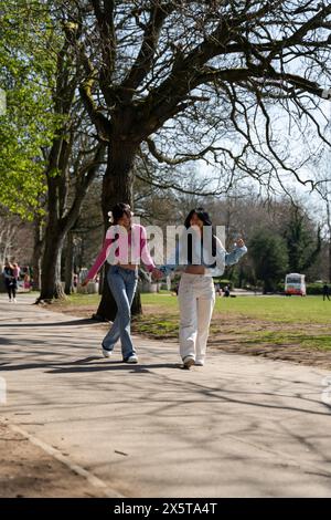Junge Freundinnen, die Hände im Park halten Stockfoto
