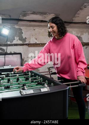 Junge Frau, die Tischfußball spielt Stockfoto