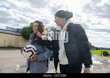Junge Freundinnen, die draußen mit Fußball laufen Stockfoto