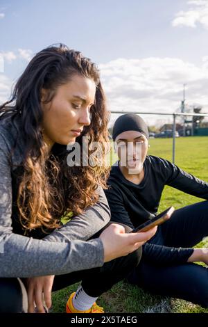 Fußballspielerinnen, die während der Pause telefonieren Stockfoto