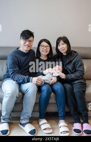 Familie in zwei Generationen mit Baby (0-1 Monate), das auf dem Sofa sitzt Stockfoto