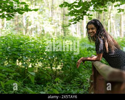 Porträt einer Frau, die sich im Wald auf Geländer stützt Stockfoto