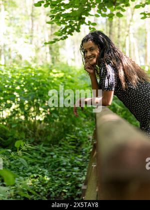 Porträt einer Frau, die sich im Wald auf Geländer stützt Stockfoto