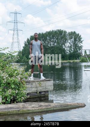 Muskulöser Mann in Sportkleidung am See Stockfoto