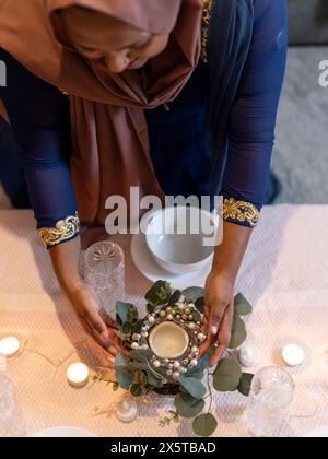 Frau, die während des Ramadan zu Hause Dekoration auf den Tisch legt Stockfoto