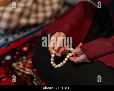 Frau, die während des Ramadan-Gebets zu Hause Gebetsperlen hält Stockfoto
