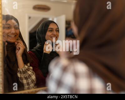 Frauen kleiden Hijabs vor dem Spiegel für die Ramadan-Feier zu Hause Stockfoto