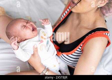 Mutter tröstet neugeborenes Mädchen im Bett zu Hause Stockfoto