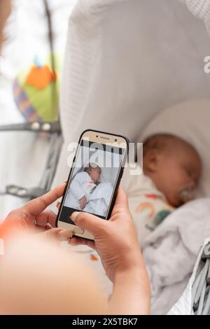 Mutter fotografiert das Neugeborene Mädchen, das im Kinderbett schläft Stockfoto