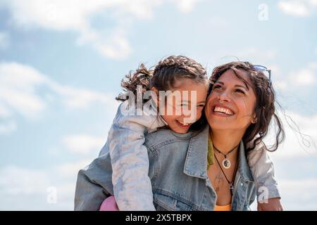 Lächelnde Mutter, die Tochter (8-9) mit Huckepack reitet Stockfoto