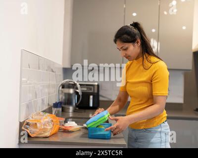 Eine junge Frau, die in der Küche Lunchpakete zubereitet Stockfoto