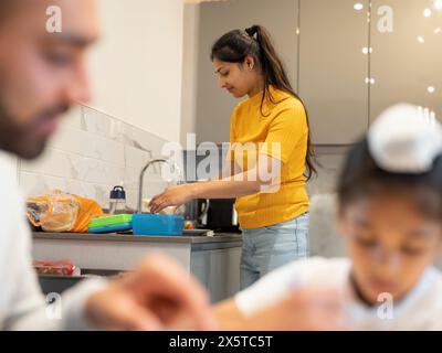 Junge Frau, die in der Küche Lunchpakete für die Familie vorbereitet Stockfoto