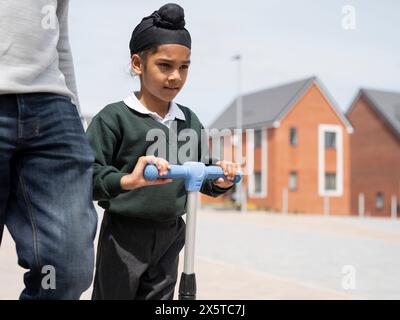 Junge (6-7) auf dem Roller, der mit Vater zur Schule geht Stockfoto