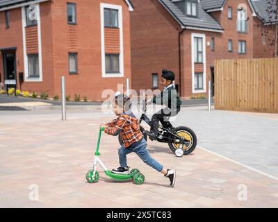 Brüder (2-3,6-7), die Fahrrad fahren und Roller schieben Stockfoto