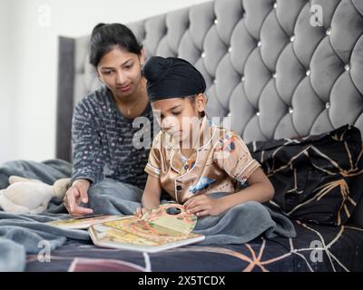 Mutter und Sohn (6-7) lesen Buch im Bett Stockfoto