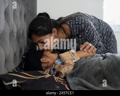 Mutter, die den Sohn ins Bett legt (6-7) Stockfoto