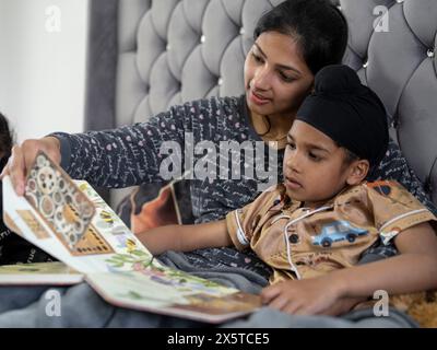 Mutter und Sohn (6-7) lesen Buch im Bett Stockfoto