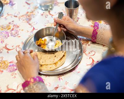 Frau, die zu Hause traditionelle indische Küche isst Stockfoto
