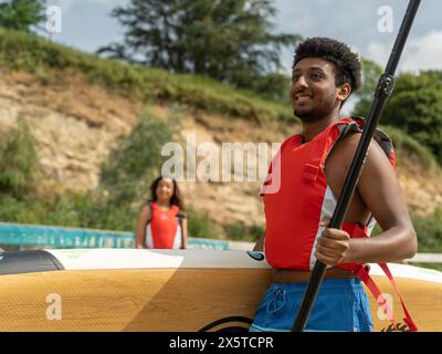 Frau, die einen Mann mit Paddleboard und Ruder ansieht Stockfoto