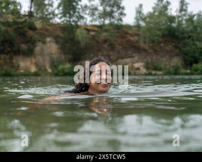 Lächelnde Frau, Schwimmen im See Stockfoto