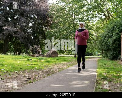 UK, Sutton, Frau im Kopftuch, die im Park joggt Stockfoto