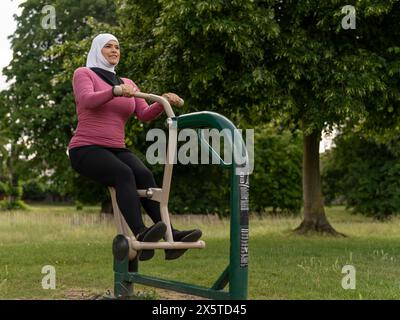 UK, Sutton, Frau im Kopftuch, die im Park Gym trainiert Stockfoto