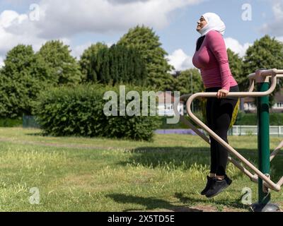 UK, Sutton, Frau im Kopftuch, die im Park Gym trainiert Stockfoto