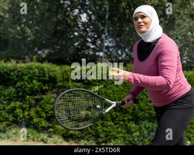 Großbritannien, Sutton, Frau im Kopftuch, die Tennis im Park spielt Stockfoto