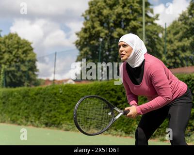 Großbritannien, Sutton, Frau im Kopftuch, die Tennis im Park spielt Stockfoto