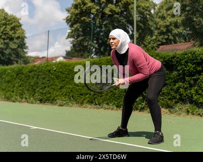 Großbritannien, Sutton, Frau im Kopftuch, die Tennis im Park spielt Stockfoto