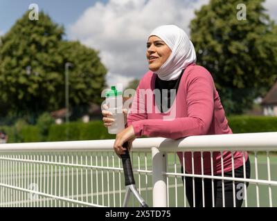 UK, Sutton, Frau im Kopftuch, die auf dem Tennisplatz ruht Stockfoto