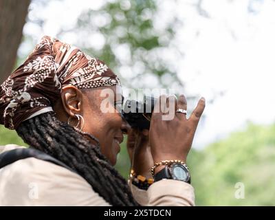 Lächelnde Wanderer, die durch das Fernglas im Wald schaut Stockfoto