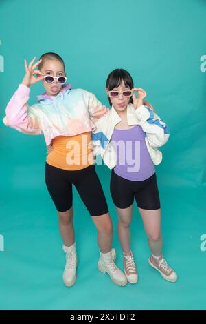 Studio-Porträt von zwei Mädchen, die eine Sonnenbrille tragen und Zungen herausragen Stockfoto