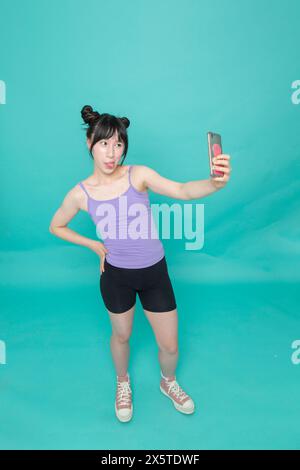 Studio-Aufnahme von Mädchen, das aus der Zunge ragt und Selfie macht Stockfoto